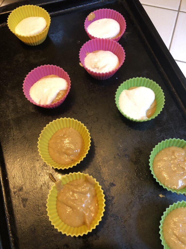 filling muffin cups with pumpkin muffin mix and cream cheese filling