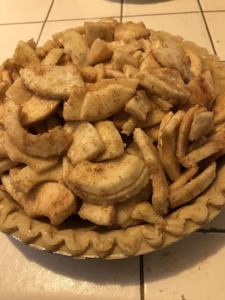 sliced apples with sugar and spices in bottom crust